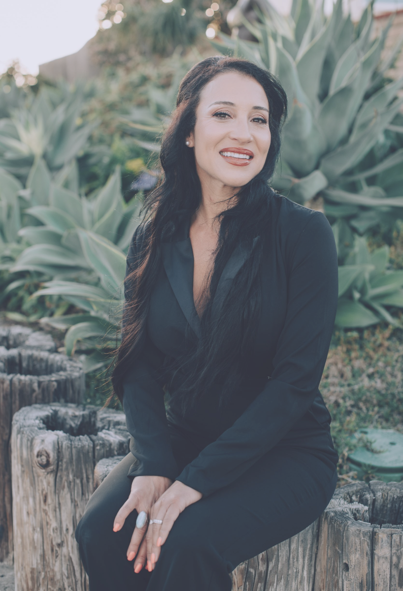 Dr. Jacqlyn Wax, PsyD, seated outdoors among coastal agave in San Diego